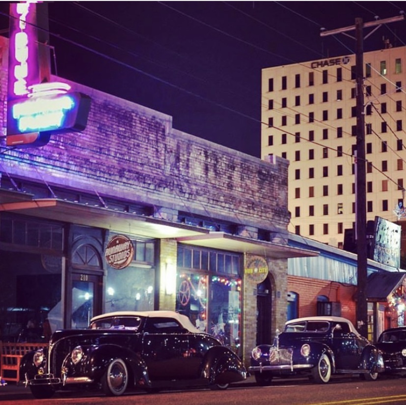 A building with neon lights and vintage cars outside